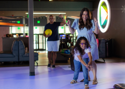 Man, woman, and daughter bowling.